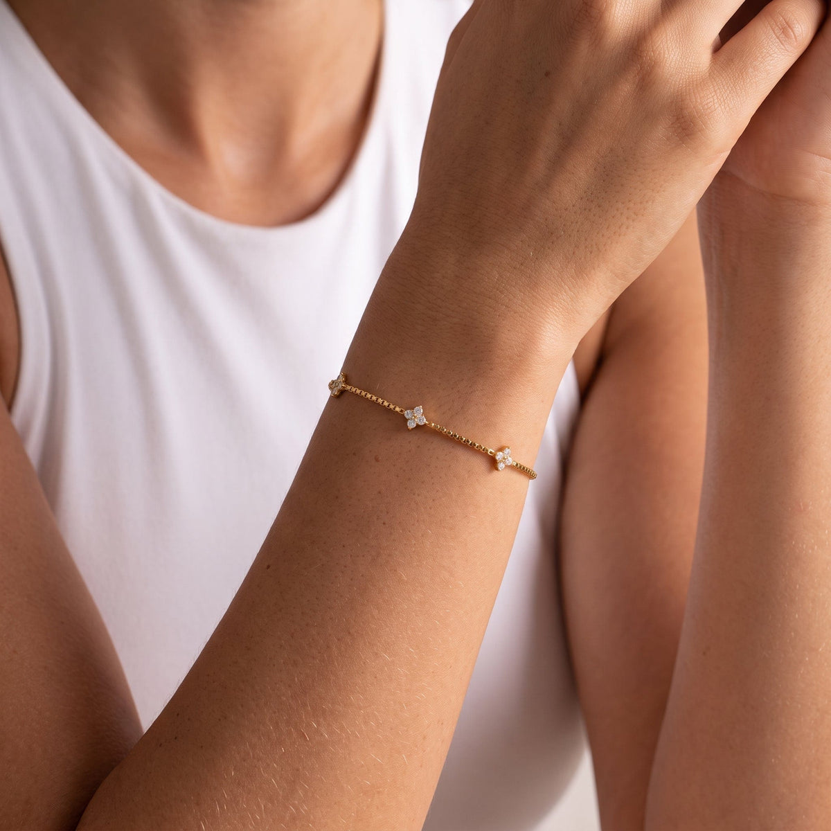 Wider view of a woman wearing the Clara crystal clover gold bracelet on the wrist