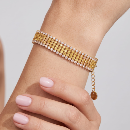 Woman wearing the Clarisse wide gold bracelet with rows of yellow and clear crystals on the wrist