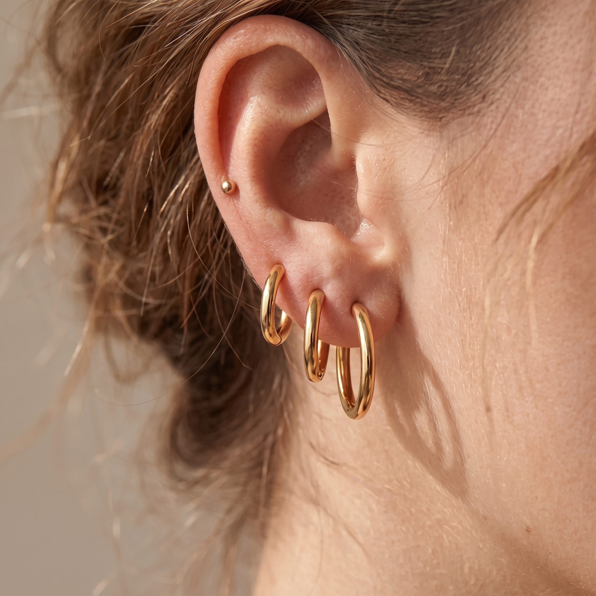 Three Classic Round gold hoops in graduated sizes stacked along the earlobe