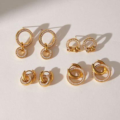 Small and large Clémence circle huggies at the front of a group of gold earrings on a sunlit surface