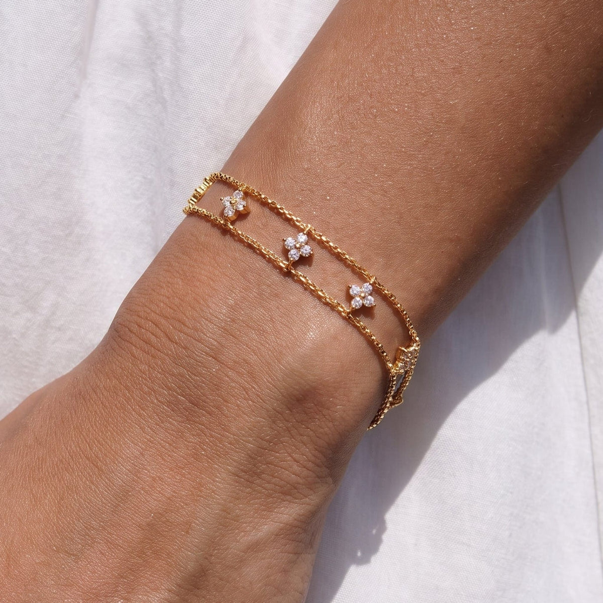 Woman wearing the Clémence layered clover gold bracelet on the wrist