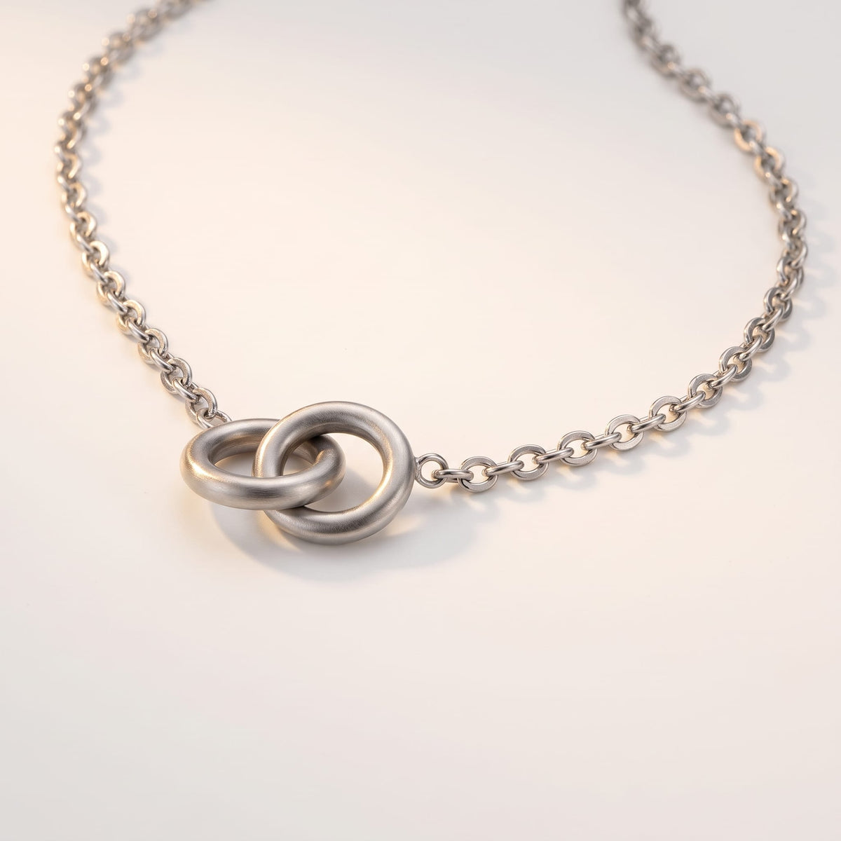 Colette interlocking rings silver necklace on a white surface with two interlocking circular pendant rings