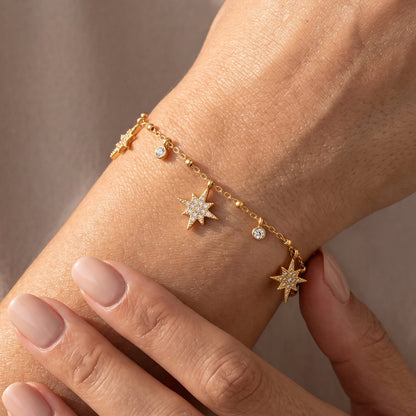 Woman wearing the Colette gold bracelet with dangling pavé star charms and round crystals on the wrist