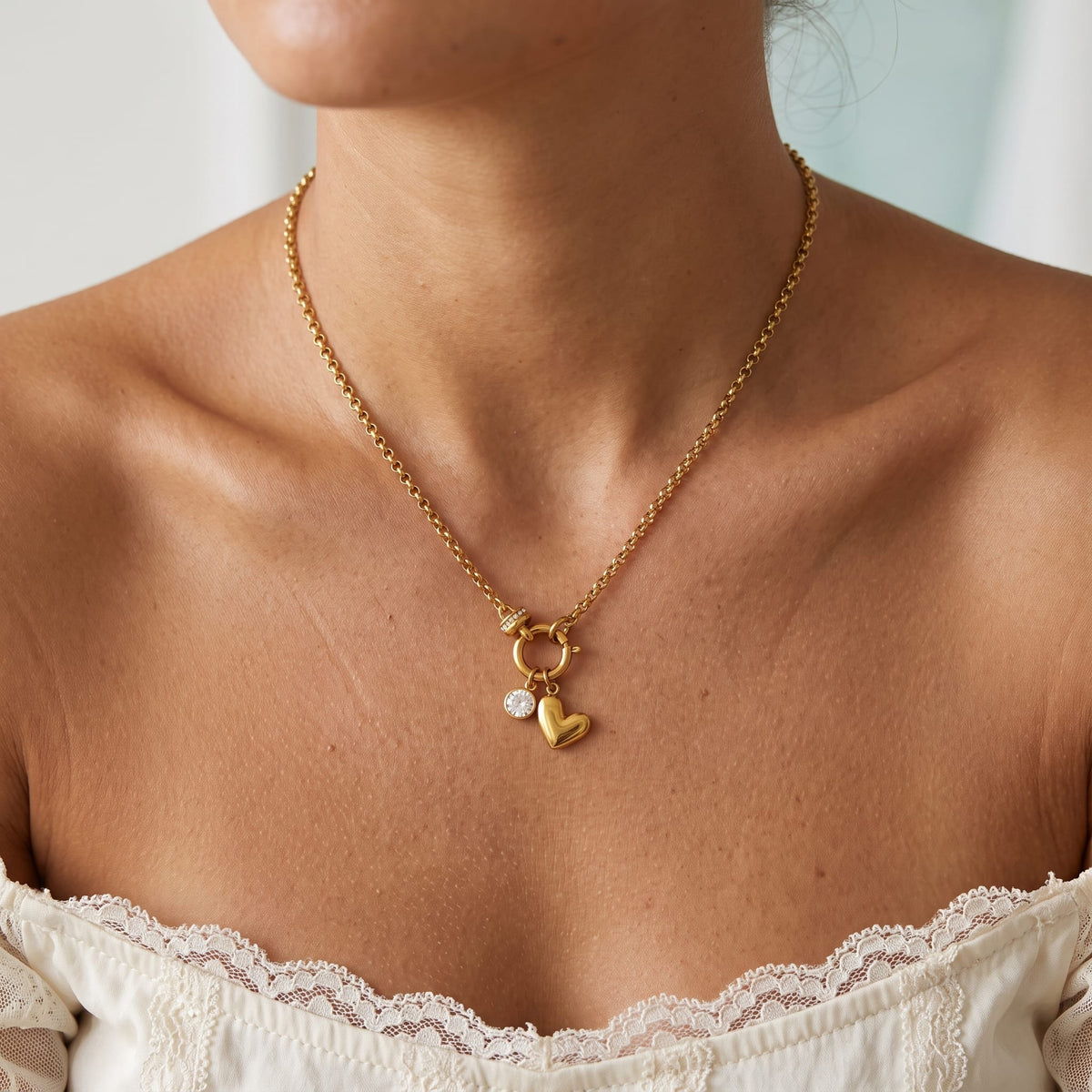Woman wearing the Daphné heart charm gold necklace at the collarbone wearing a lace top