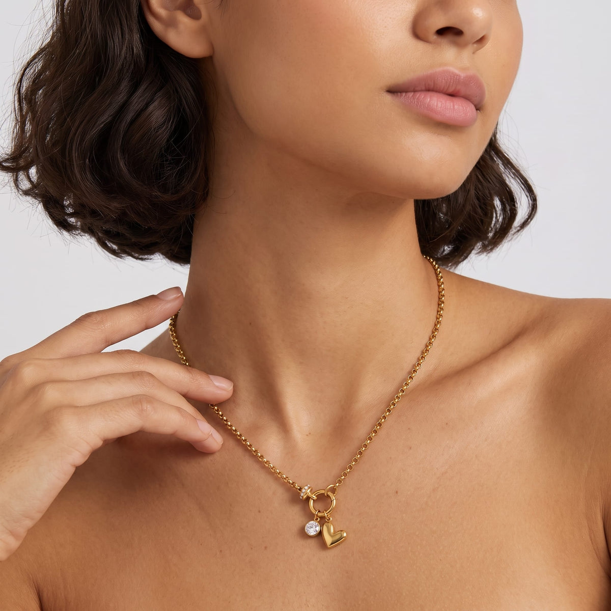Woman wearing the Daphné heart charm gold necklace at the collarbone touching her neck
