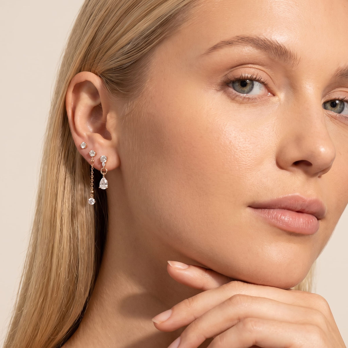 Woman wearing the Delfina drop trio gold earrings on the ear with hand under chin