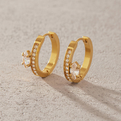 Pair of Diletta pavé huggie hoops with marquise crystals standing on a sandy stone surface