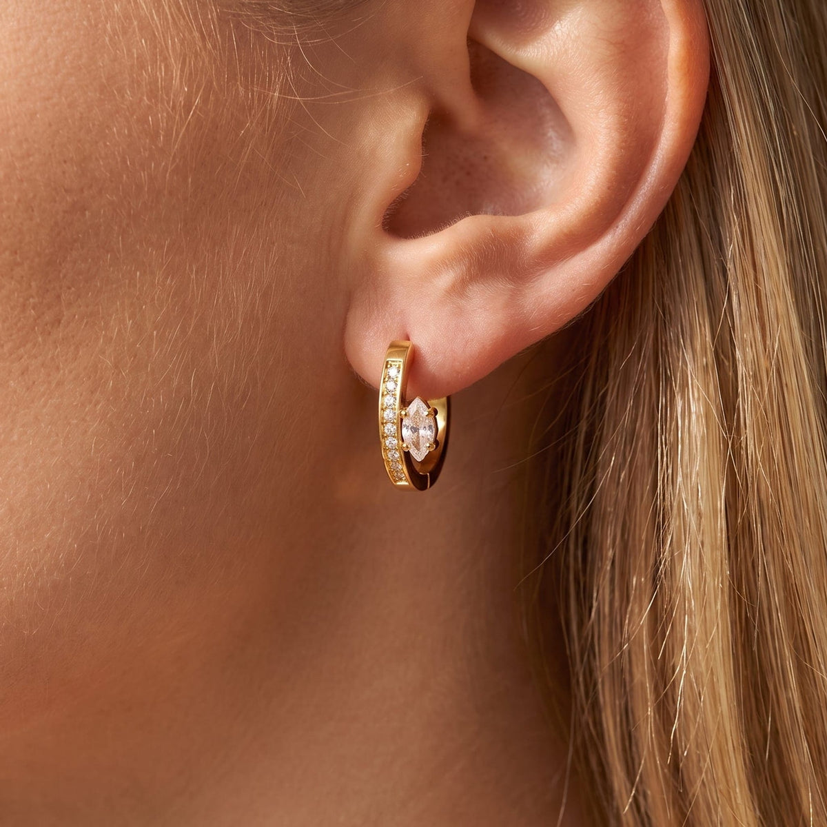 Woman wearing the Diletta marquise huggie gold earrings on the ear