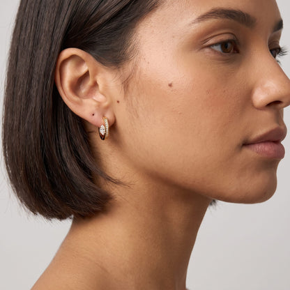 Woman wearing the Diletta marquise huggie gold earrings on the ear in profile view
