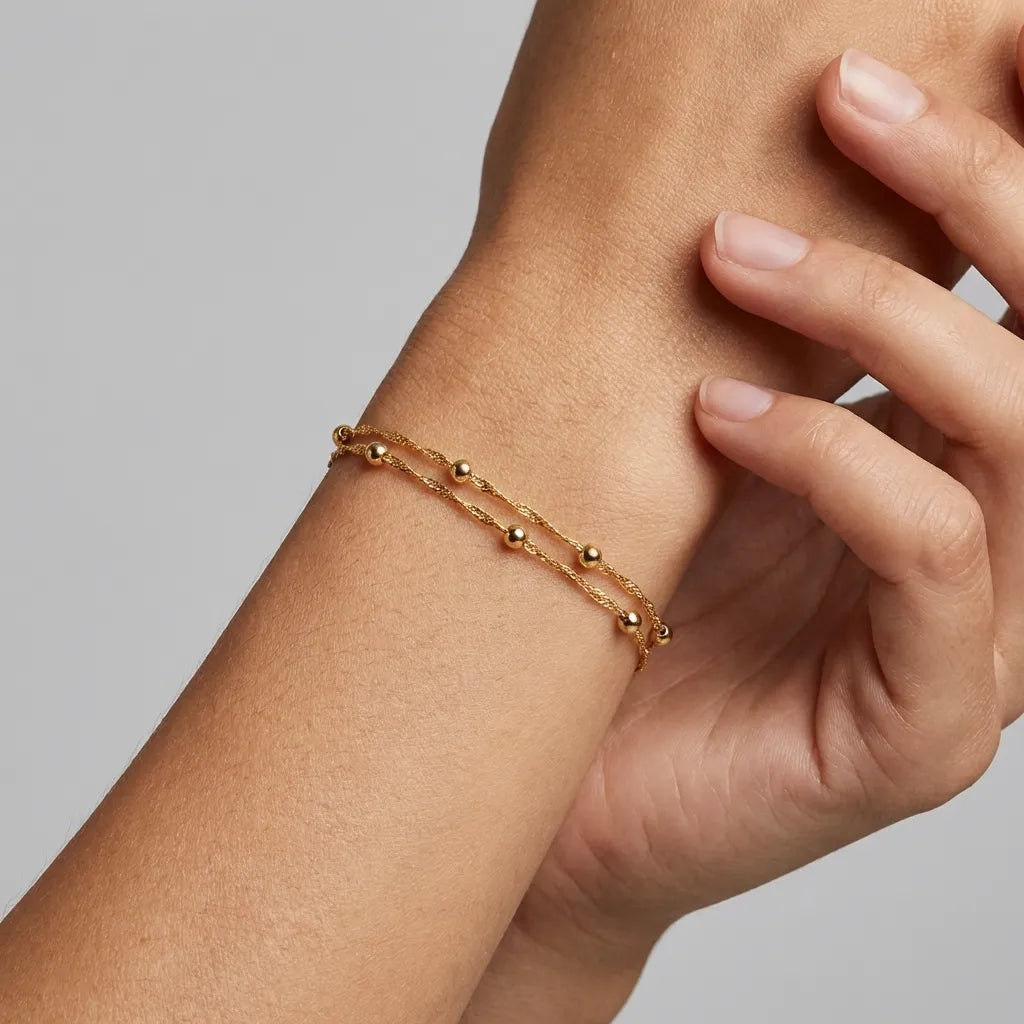Elena Double Bead bracelet in gold on the wrist, two twisted chains dotted with small polished beads