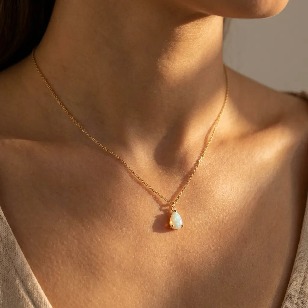 Woman wearing the Sophie gold necklace with a teardrop opal pendant at the collarbone