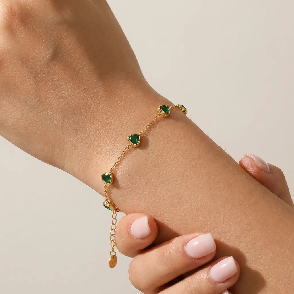Woman wearing the Francia gold chain bracelet with green heart crystals and extender on the wrist