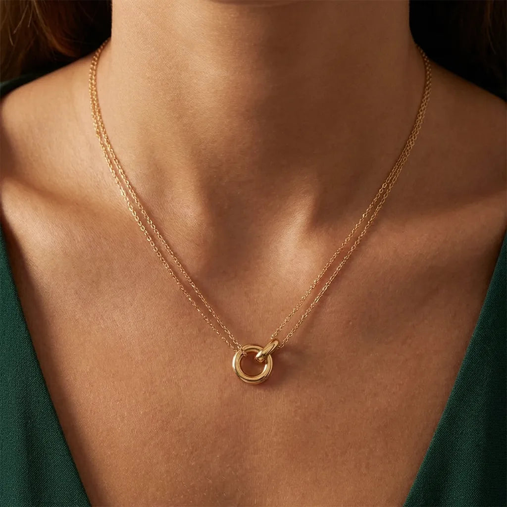 Woman in a green top wearing the Harper double chain gold necklace with a circle pendant