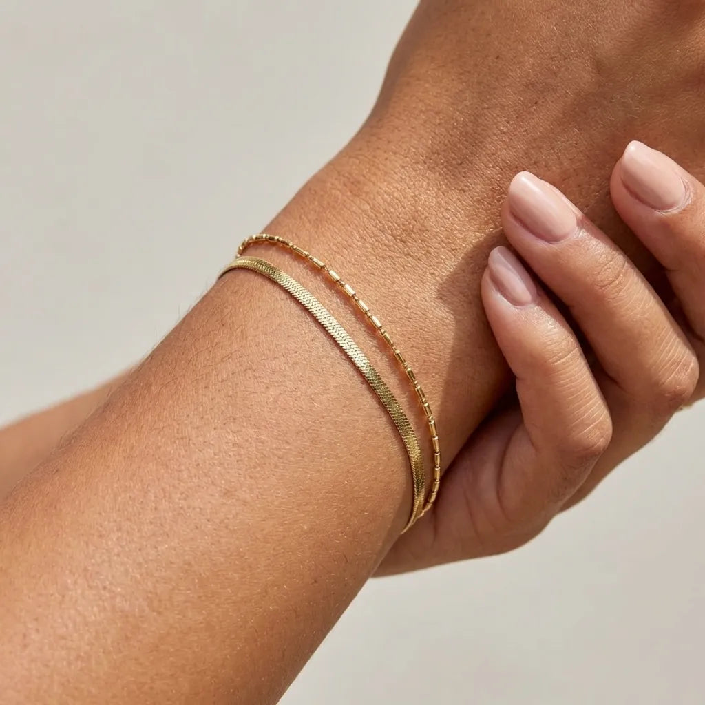 Vida gold herringbone chain and tube bead bracelet stacked on the wrist
