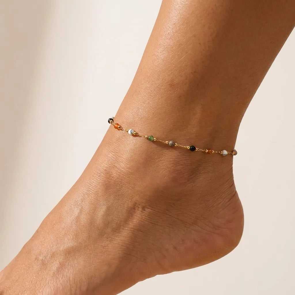 Aurélie color bead anklet on the ankle, small multicolored beads spaced along a fine gold chain