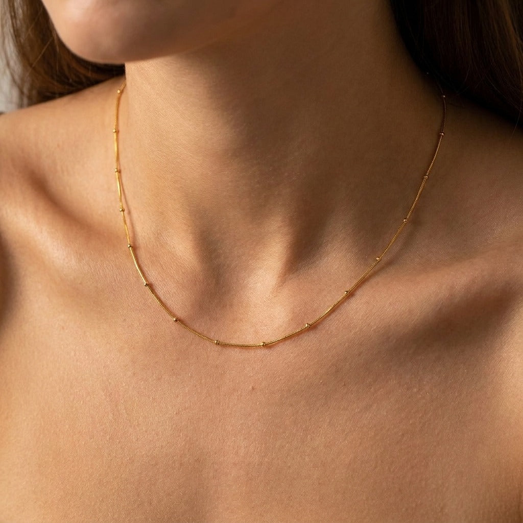 Woman wearing the Elise dainty gold necklace, a fine beaded chain resting at the collarbone