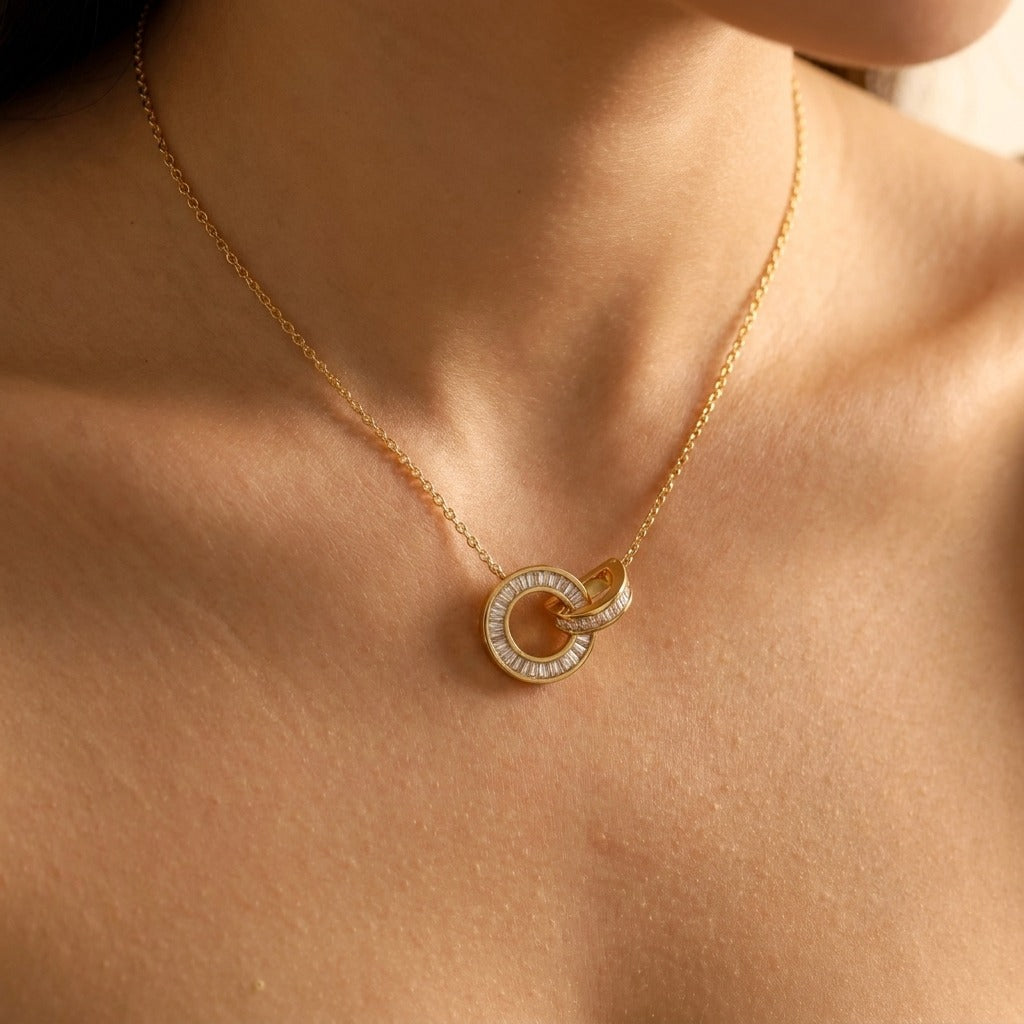 Woman wearing the Amira gold necklace with two interlocking crystal-set circles
