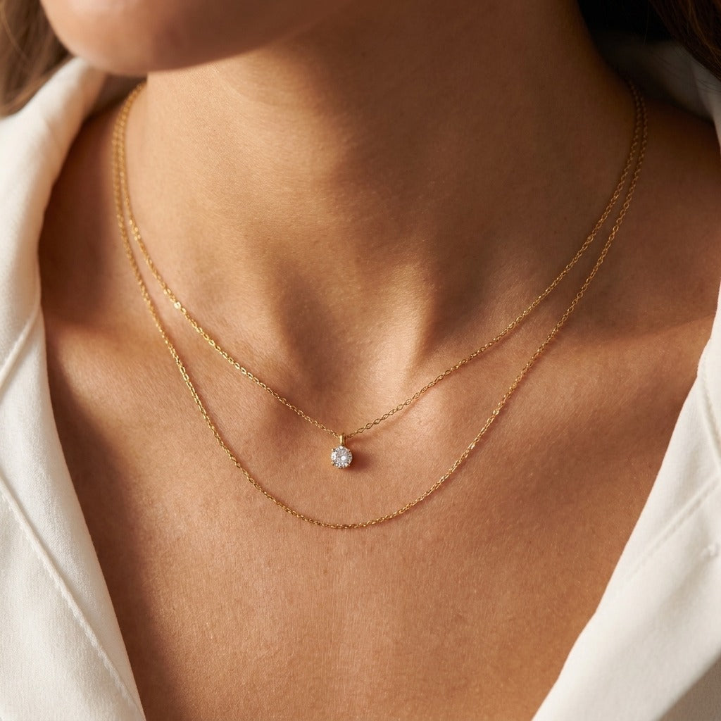 Woman wearing the Diana layered gold necklace, a single crystal solitaire above a plain chain