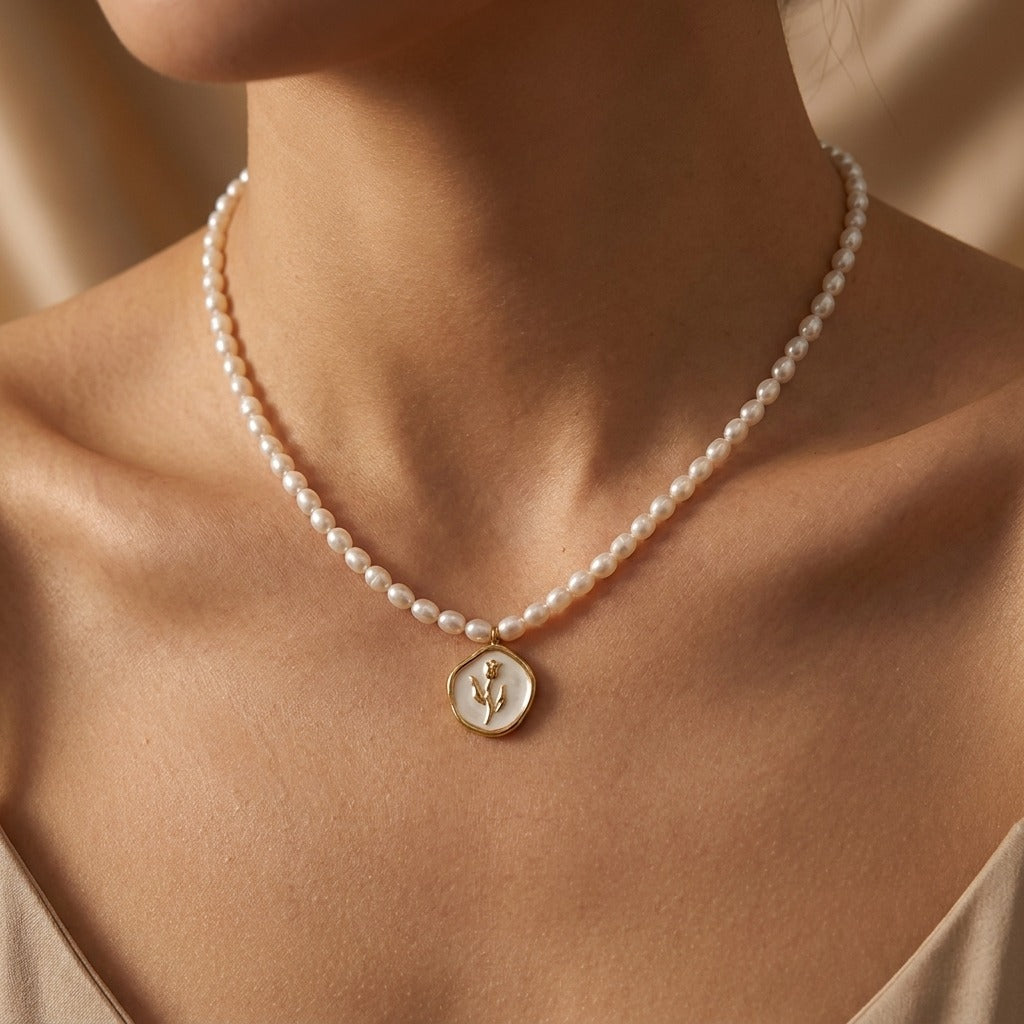 Woman wearing a pearl strand necklace with a gold tulip disc pendant resting below the collarbone