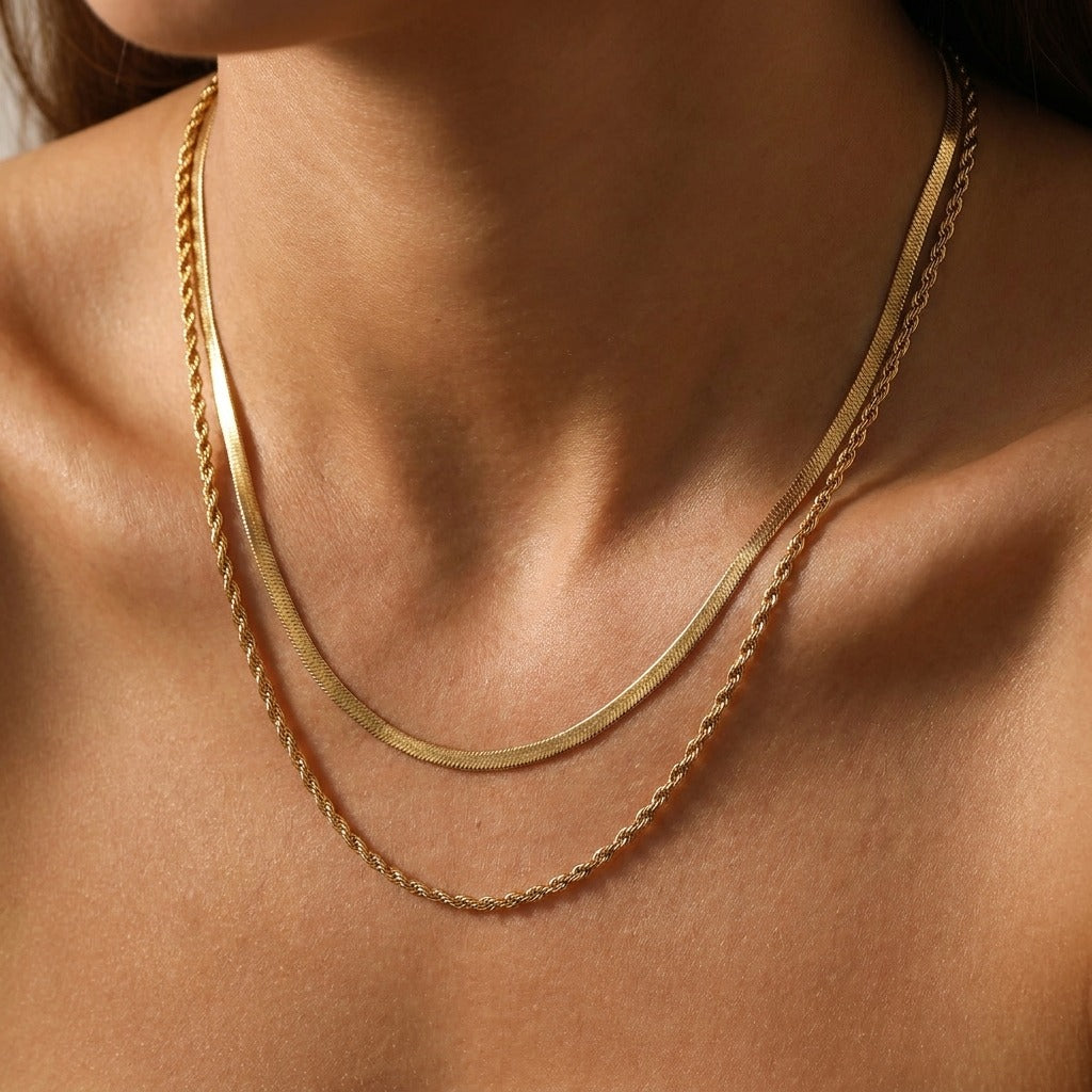 Woman wearing the Hailey layered gold necklace, a herringbone chain above a twisted rope chain