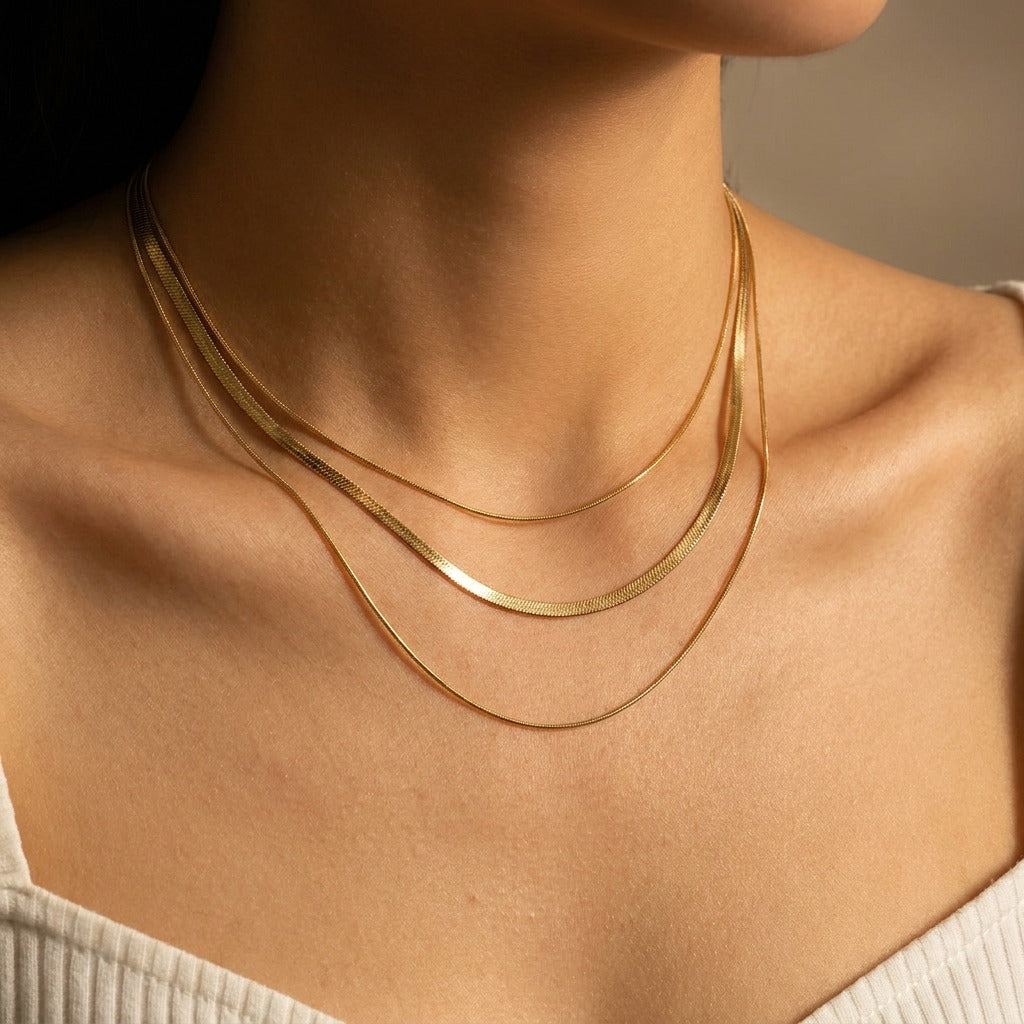Woman wearing the Zafina pre-layered gold necklace with a flat herringbone between two fine chains
