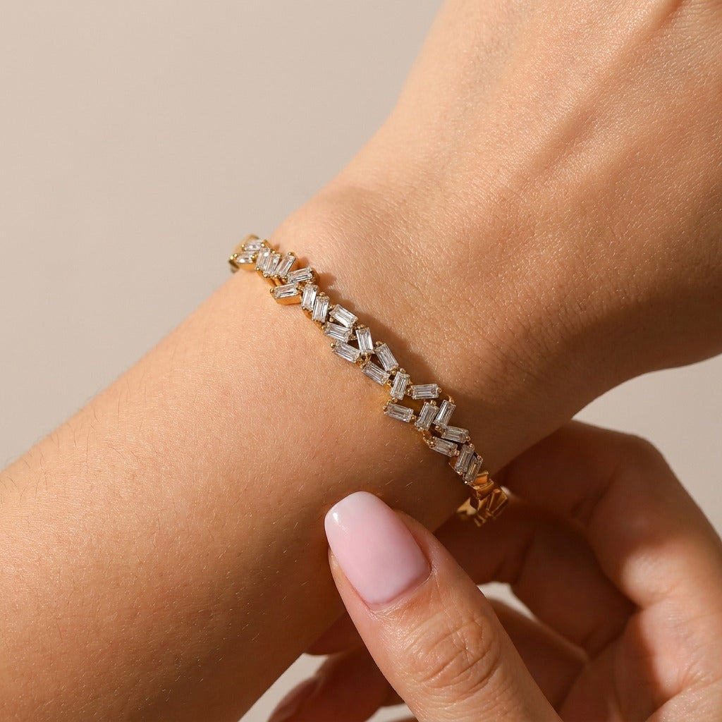 Amélie radiant gold bangle on the wrist, baguette crystals scattered at angles across the front