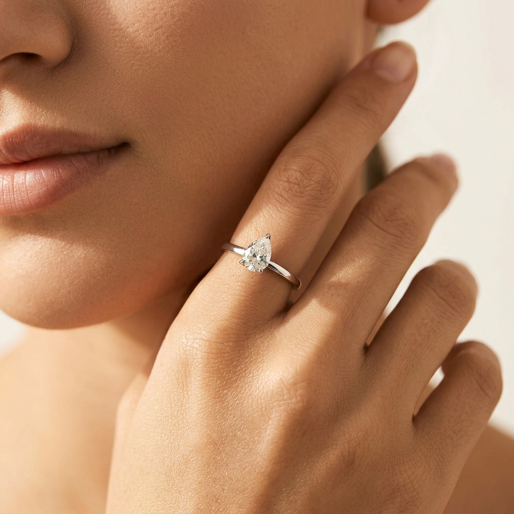 Woman wearing the Eva crystal drop silver ring, a pear-shaped crystal on a thin band, hand at her jaw