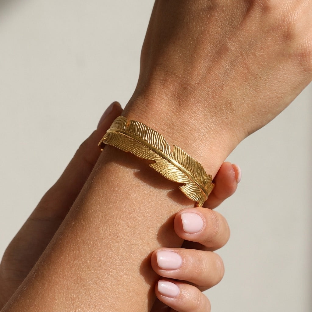 Woman wearing the Angel gold bangle, an etched feather cuff wrapped around the wrist
