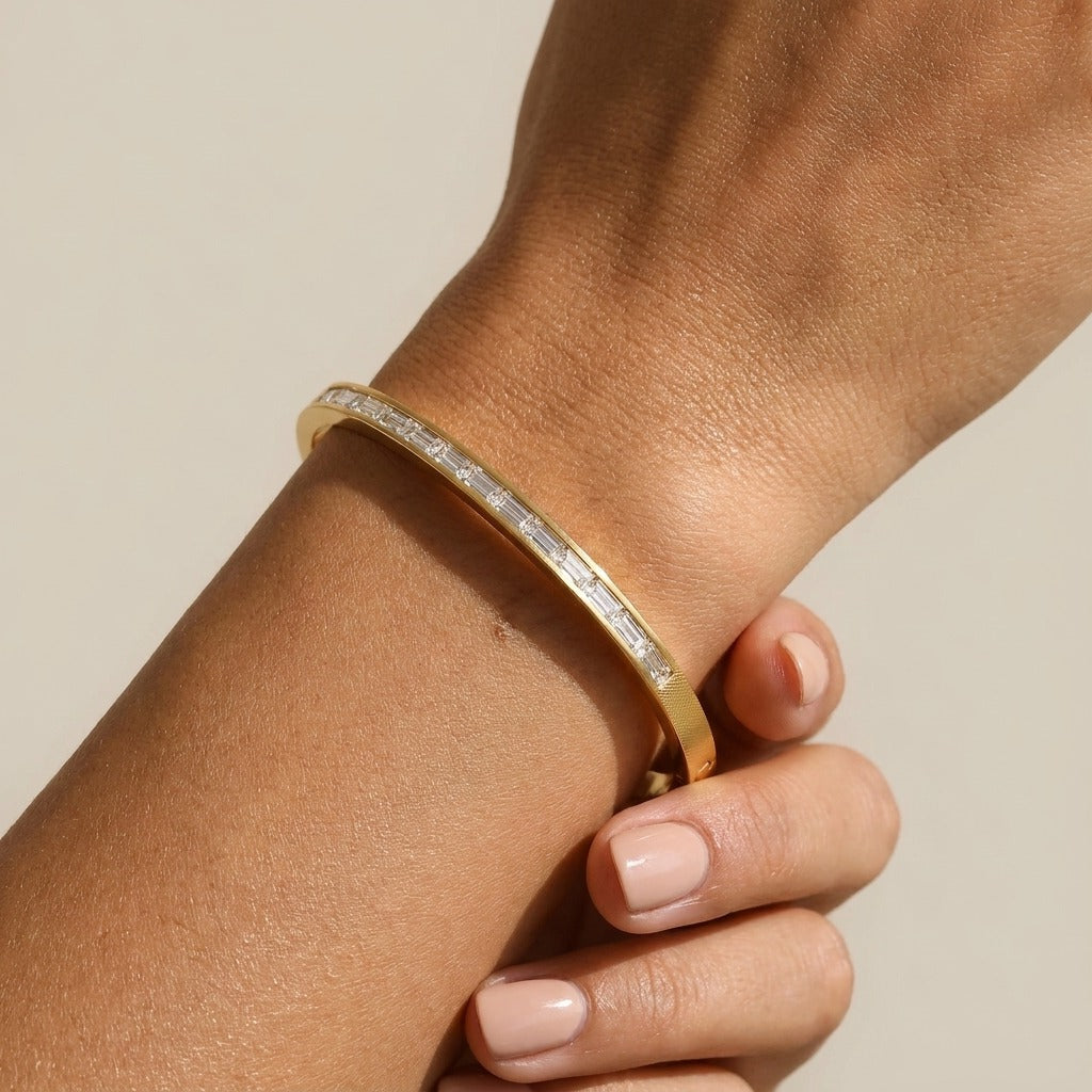 Woman wearing the Grace gold bangle with a channel-set row of baguette-cut crystals on the wrist