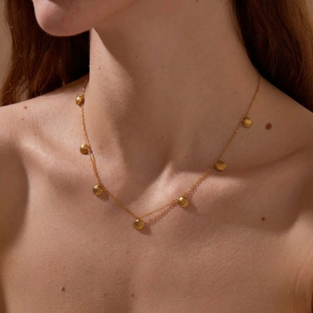 Woman wearing the Sirena gold shell necklace, scallop shell charms along the collarbone