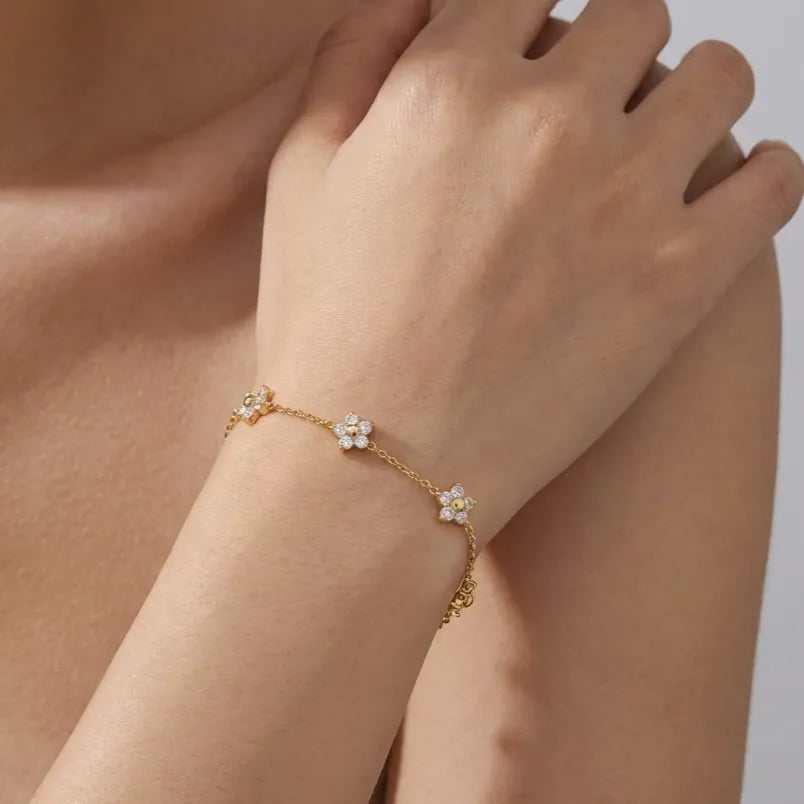 Woman wearing the Mia flower crystal bracelet in gold with crystal flowers spaced along the chain