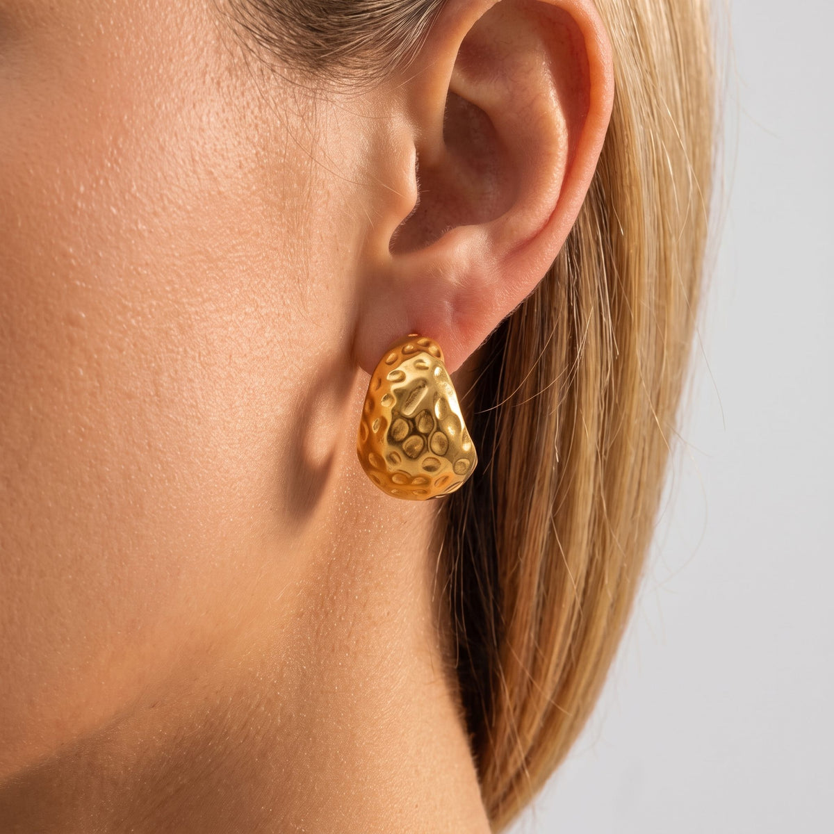 Woman wearing the Eira hammered gold C-hoop earring, seen in profile