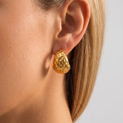Woman wearing the Eira hammered gold C-hoop earring, seen in profile