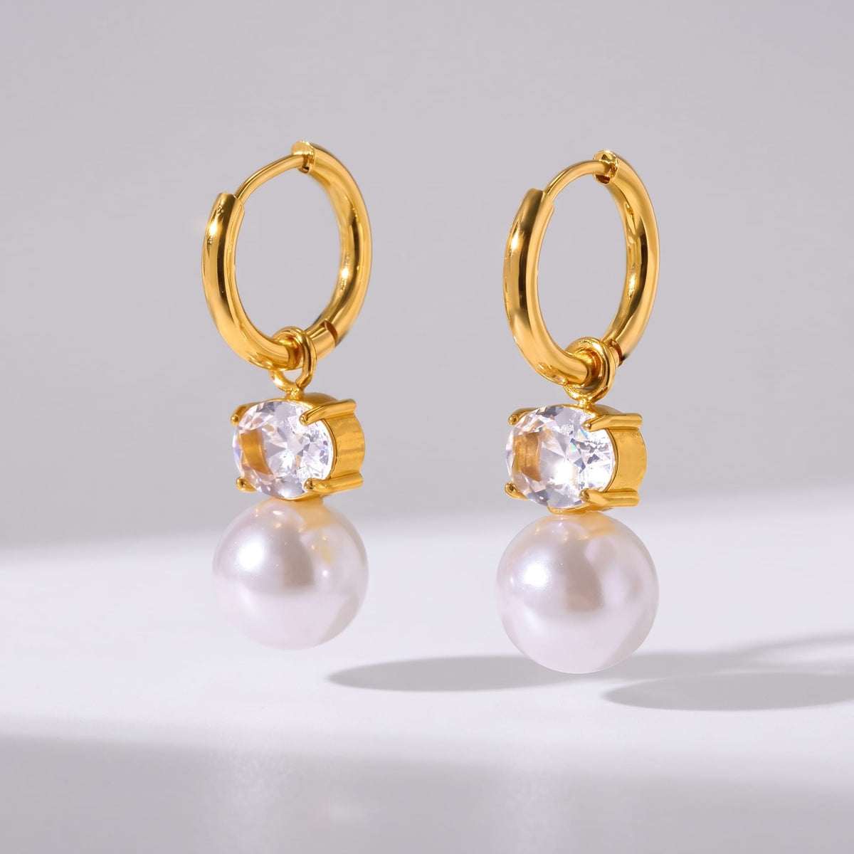 Eléonore pearl drop gold earrings on a white surface with soft shadows