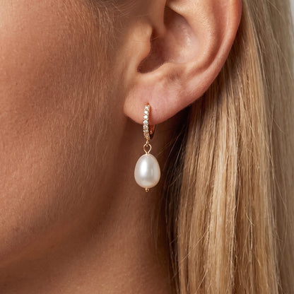 Woman wearing the Élise baroque pearl earring, an oval pearl hanging from a crystal gold huggie