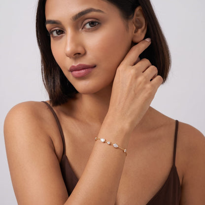 Woman wearing the Élise teardrop crystal gold bracelet on the wrist in a brown strap top
