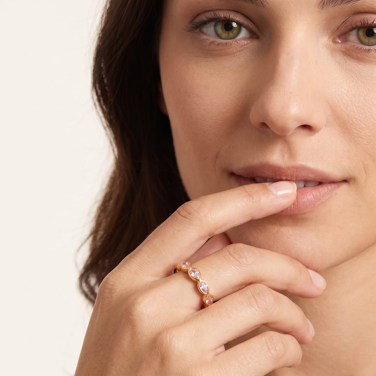 Woman wearing the lodie pink pear gold ring on the hand touching her lip
