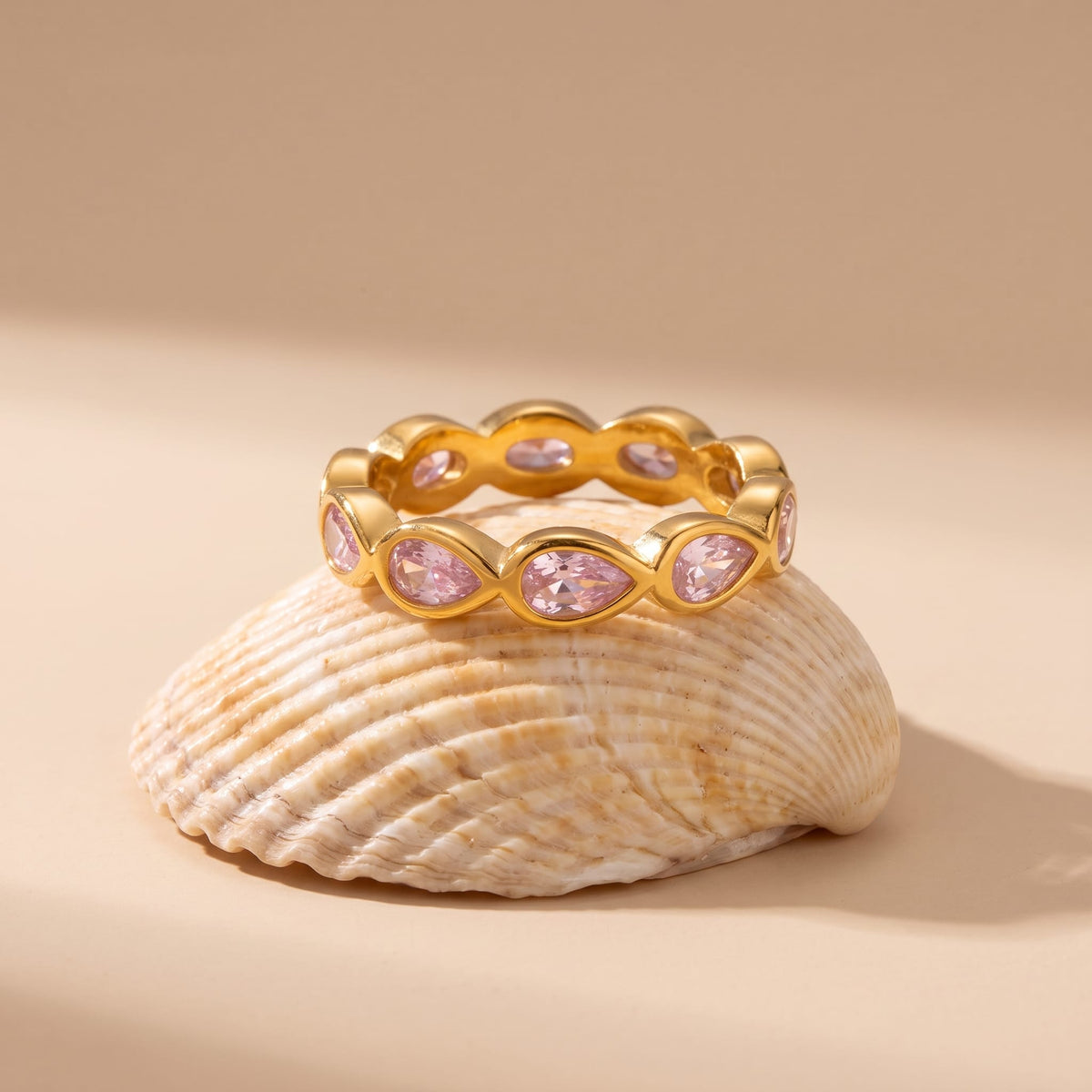 lodie pink pear gold ring on a beige seashell resting in warm natural light