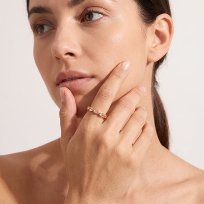 Woman wearing the lodie pink pear gold ring on the hand resting near her chin