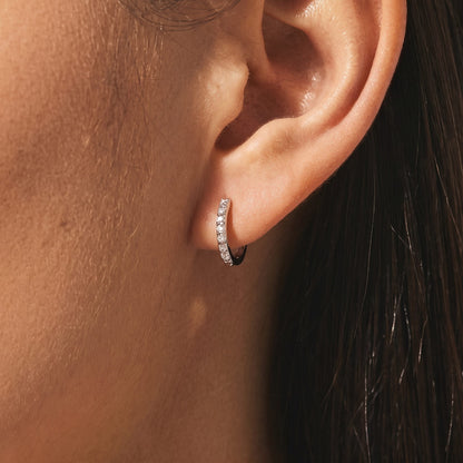 Woman wearing an Emma pavé silver huggie hoop with a row of clear crystals on her lobe