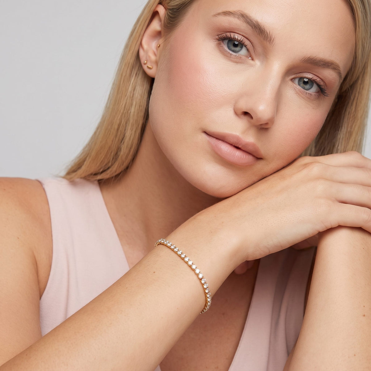 Blonde woman resting her chin on her arms, wearing the Emma tennis chain gold bracelet