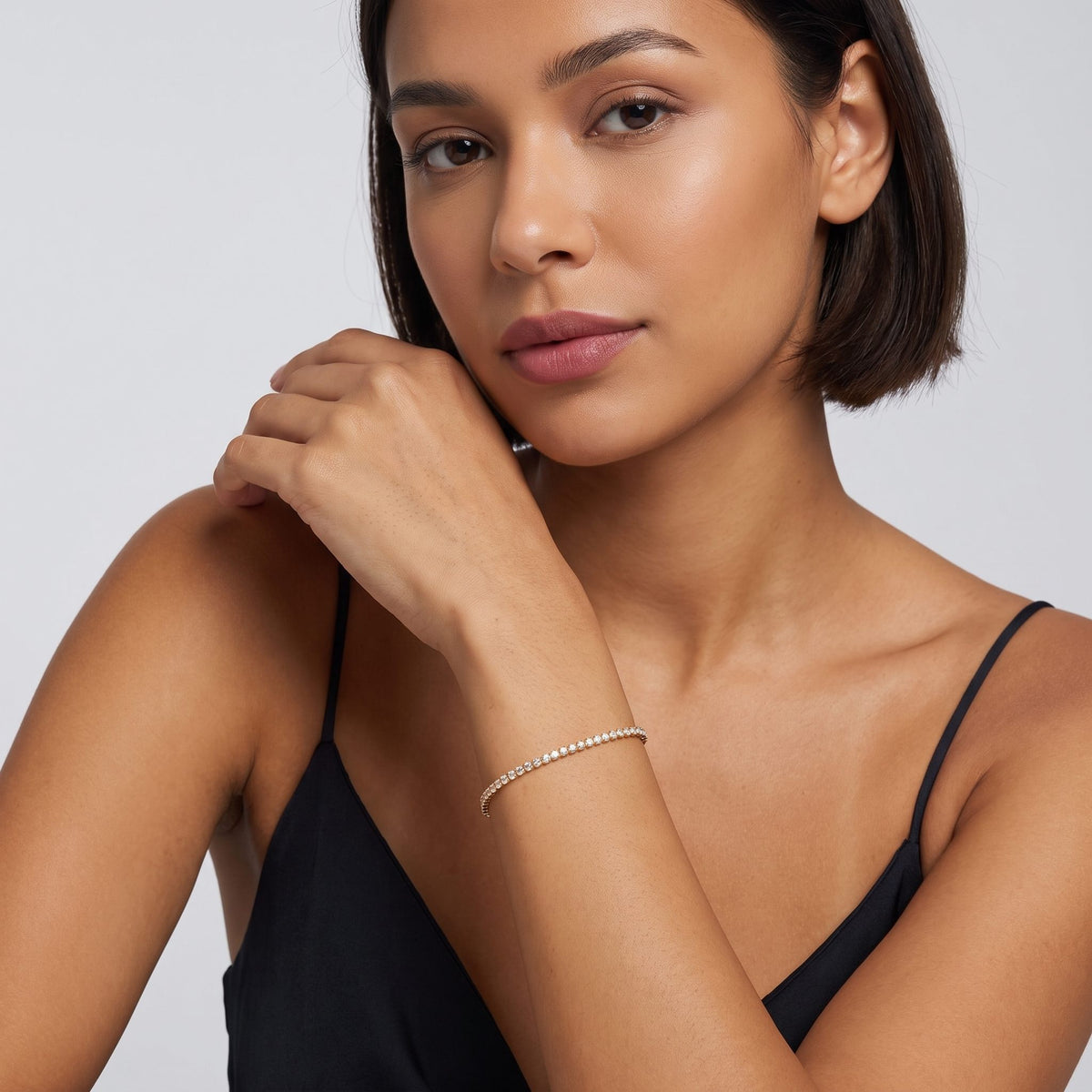 Woman with a dark bob wearing the Emma tennis chain gold bracelet near her chin