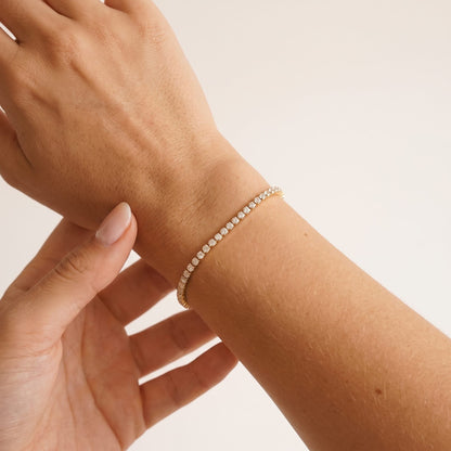 Wider view of a woman wearing the Emma tennis chain gold bracelet on the wrist