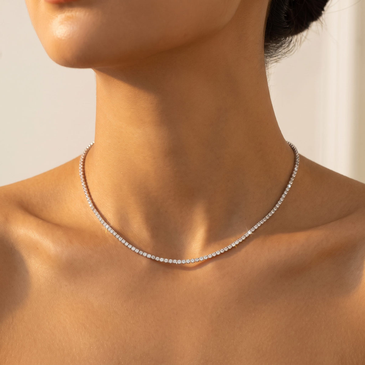 Close-up of a woman wearing the Emma tennis chain silver necklace at the base of her neck