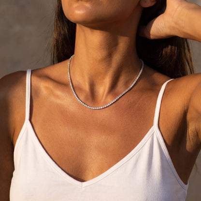 Woman in a white camisole wearing the Emma tennis chain silver necklace in warm evening light