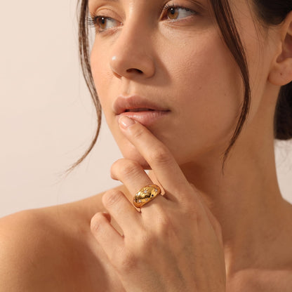 Woman wearing the Estelle star dome gold ring on the hand touching her lip in medium close-up