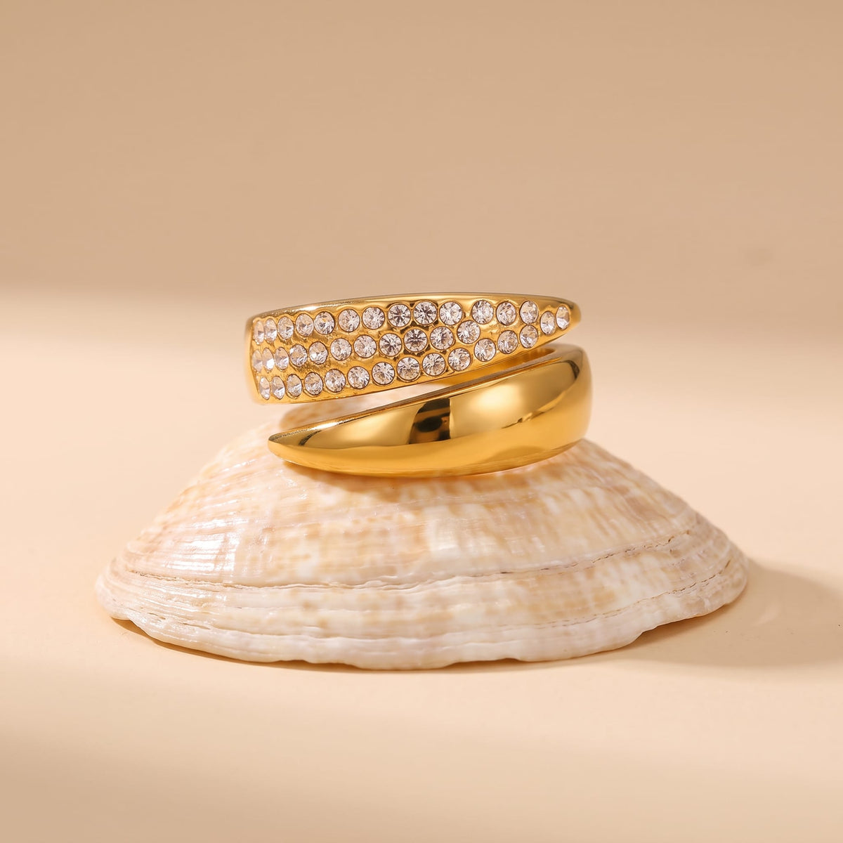 Evelyne pavé wrap gold ring on a seashell against a neutral background