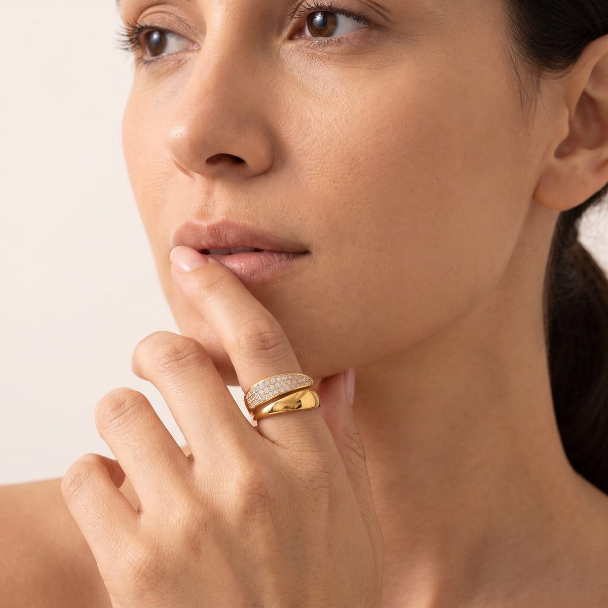 Woman wearing the Evelyne pavé wrap gold ring on the hand resting near her chin