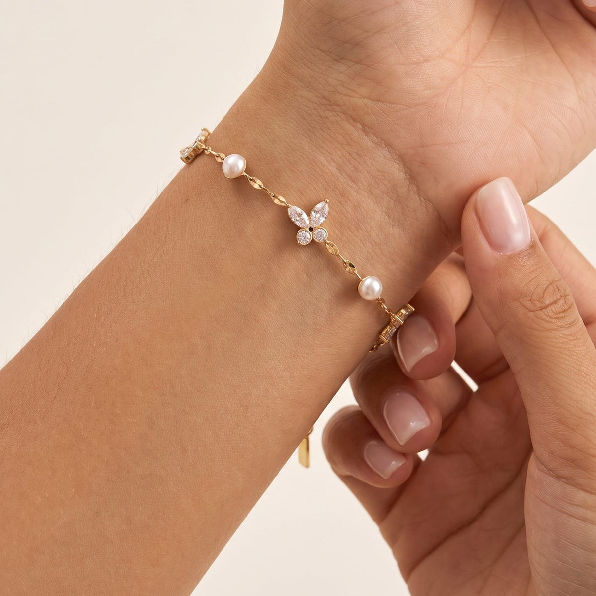Woman wearing the Fabiola crystal butterfly gold bracelet on the wrist, holding her arm