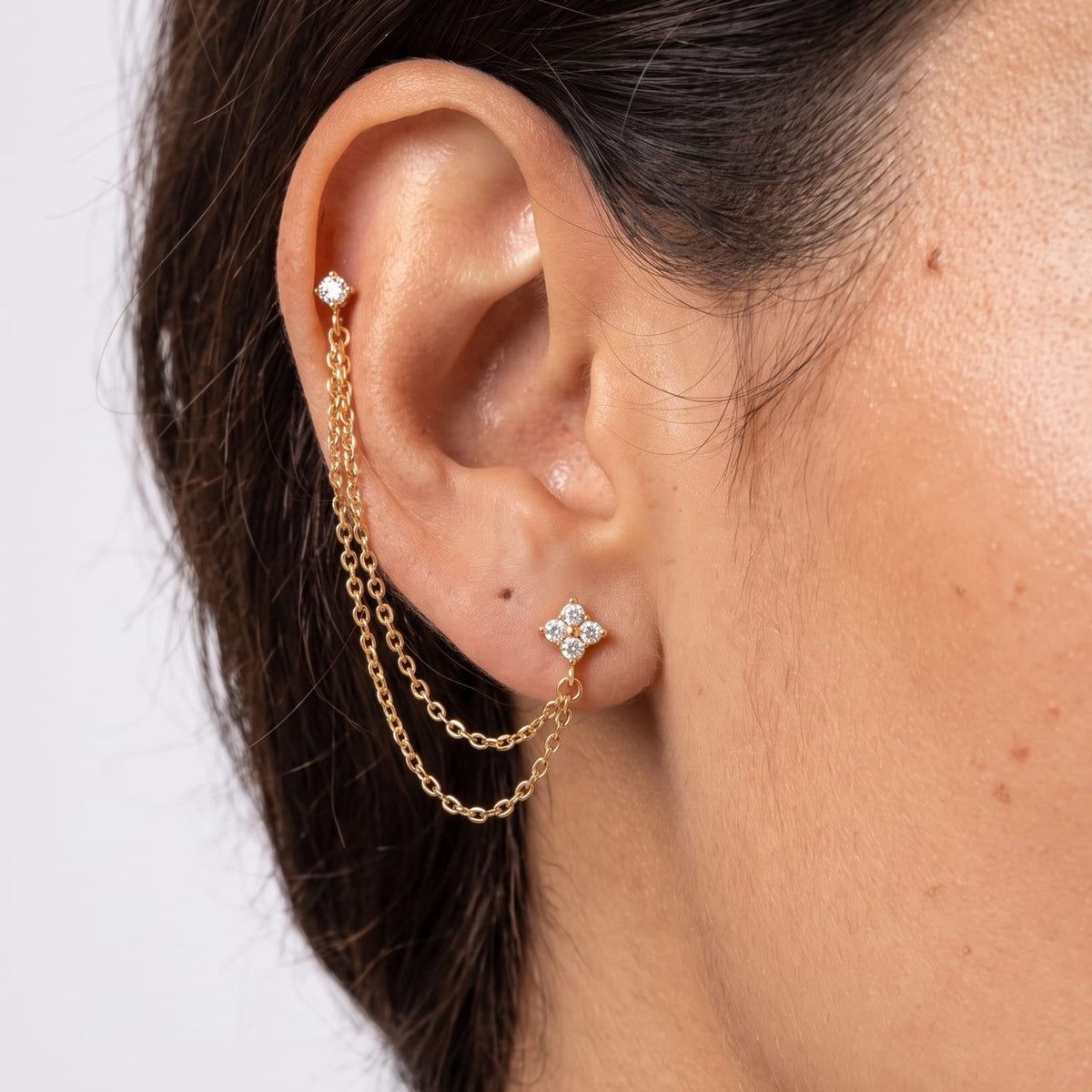Woman wearing the Félicie flower chain gold earrings on her ear in a close-up profile shot